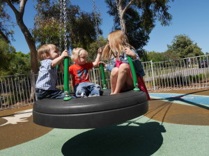 Playing on the tire swing at the playground.